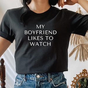 a woman with black hair and a shirt that says my boyfriend likes to watch