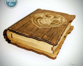 Könnte beinhalten: Holzkiste in Buchform mit einem Drachen und einem 20-seitigen Würfel, die auf den Deckel graviert sind. Die Kiste ist aus hellem braunem Holz mit rustikalem Finish.