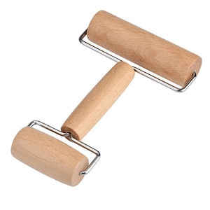 May include: A wooden rolling pin with a metal frame. The rolling pin has a handle in the middle and two rolling sections.