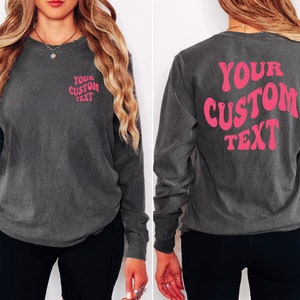 Może przedstawiać: Długi rękaw t-shirt w ciemnoszarym kolorze z r&oacute;żowym napisem z tyłu, kt&oacute;ry brzmi "YOUR CUSTOM TEXT".
