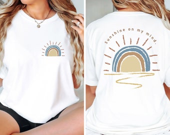 May include: White t-shirt with a rainbow and sun graphic on the front and the text "Sunshine on my mind." on the back.