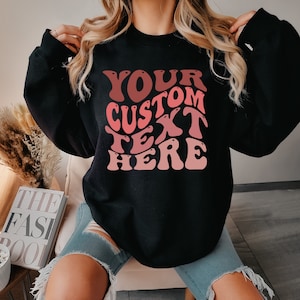 May include: Black sweatshirt with a pink and red gradient graphic that says "YOUR CUSTOM TEXT HERE" in a retro font.