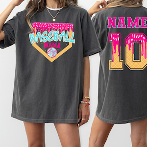 May include: Two black t-shirts with a baseball theme. The front shirt has a pink and blue baseball graphic with the text "Baseball Mama". The back shirt has the text "NAME" and the number "10" in a pink and yellow ice cream cone design.