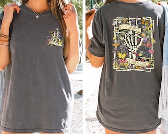 May include: A gray oversized t-shirt with a floral and butterfly graphic on the back. The graphic features a skeleton hand making a peace sign with the text "Good Energy is Contagious".