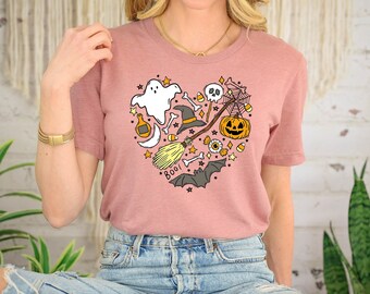 May include: A pink t-shirt with a heart-shaped design featuring various Halloween-themed illustrations, including a ghost, a witch's hat, a broom, a pumpkin, a skull, and the word "BOO!"