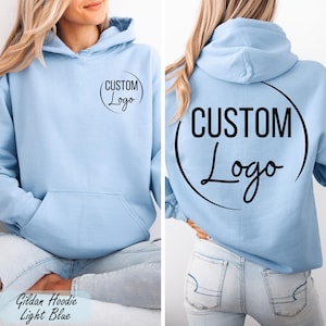 A woman wearing a light blue hoodie with the text "CUSTOM Logo" printed on the back.