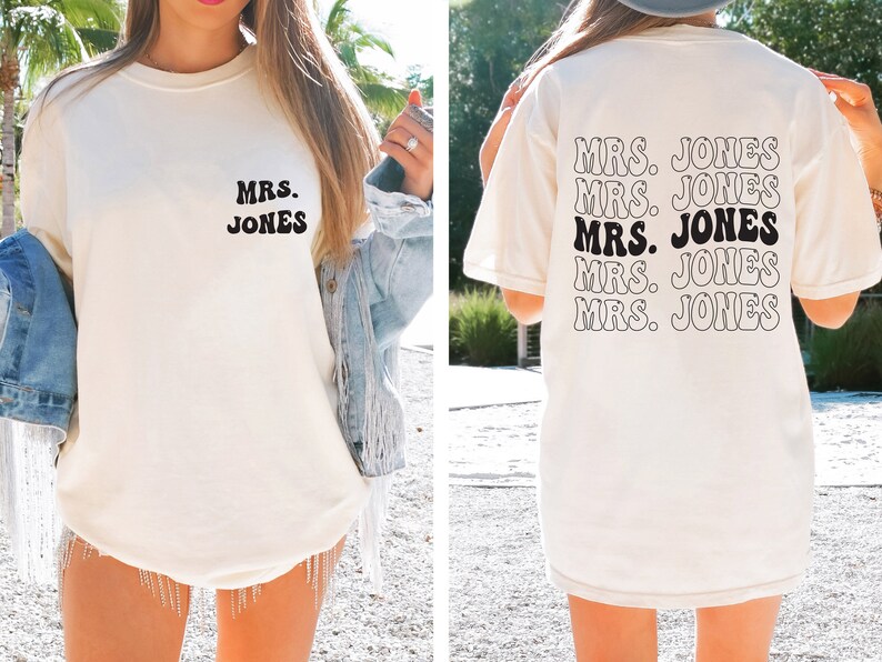 May include: Cream-colored t-shirt with the text "MRS. JONES" in a retro font on the front and back. The back of the shirt repeats the text multiple times. A casual, everyday wear item.