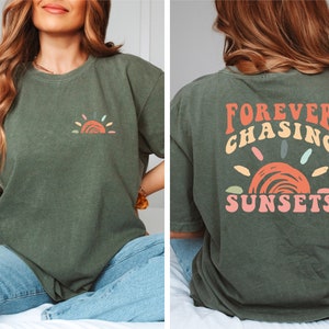 May include: A green t-shirt with a small, colourful sun graphic on the front and the text "FOREVER CHASING SUNSETS" in colourful letters on the back.
