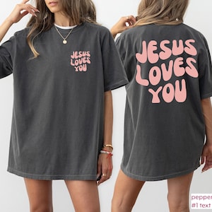 a woman wearing a jesus loves you t - shirt