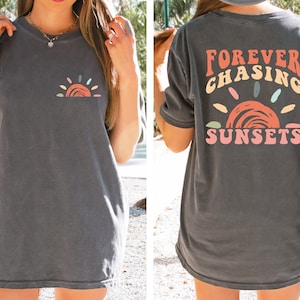 May include: A grey oversized t-shirt with a colourful sunset graphic and the text "FOREVER CHASING SUNSETS" on the back.