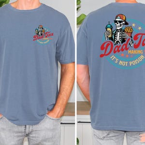 May include: Blue short-sleeve t-shirt with a graphic on the front and back. The front graphic says "Dad Tax" with a skeleton driving a car. The back graphic says "Dad Tax, making sure it's not poison" with a skeleton holding a drink and fries.