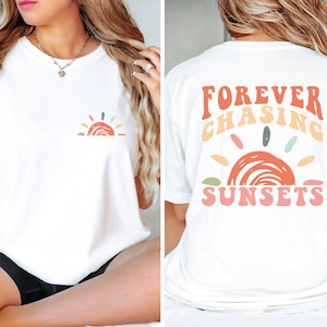 May include: White t-shirt with a colourful sunset graphic on the front and the text "FOREVER CHASING SUNSETS" on the back.