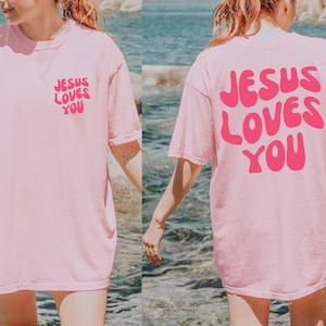 a woman in a pink jesus loves you t - shirt