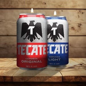 May include: Two Tecate beer cans repurposed as candles. One can is red and says "Original", the other is blue and says "Light". Each can features a black eagle logo and a burning candle wick.
