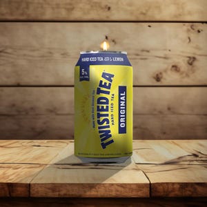 May include: A yellow and blue Twisted Tea can with a lit candle on top. The can reads "HARD ICED TEA" and "ORIGINAL". The background is a wooden surface.