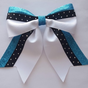 May include: A white cheer bow with teal and black glitter ribbon and black rhinestones.