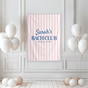 May include: A pink and white striped banner with the text "Sarah's BACH CLUB PALM BEACH, FLORIDA" in navy blue. White balloons are clustered on the left and right sides of the banner, with additional balloons on the floor.