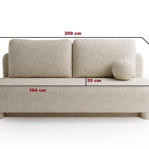 May include: A cream-colored, two-seater sofa with rounded edges and a soft, textured fabric. The sofa is 76 inches wide, 38 inches deep, and 38 inches high. It features two large back cushions and a round bolster pillow. The sofa's overall length is 82 inches.