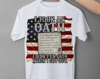 Puede incluir: Camiseta blanca con un gráfico de la bandera estadounidense y el texto "I TOOK AN OATH" y "I DIDN'T UN-OATH WHEN I GOT OUT." La camiseta también incluye el juramento de alistamiento.
