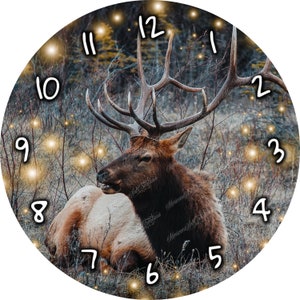 May include: A clock with a brown and white elk lying down in a forest setting. The clock face has a dark background with white numbers and gold glitter accents.