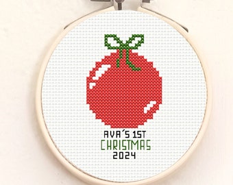 May include: A white embroidery hoop with a red and green Christmas ornament design. The text "AVA'S 1ST CHRISTMAS 2024" is embroidered below the ornament.
