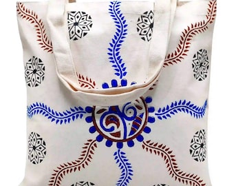 May include: A white canvas tote bag with a blue and red floral design. The bag has two long straps.