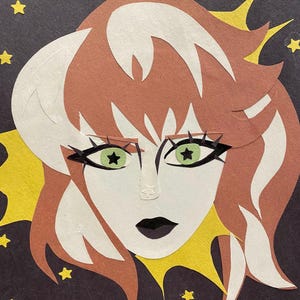 May include: A paper collage portrait of a woman with white skin, green star-shaped eyes, and black lipstick. Her hair is brown and white, with a yellow burst behind her head and yellow star accents on a dark background.