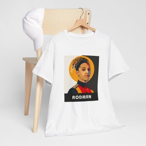 May include: White t-shirt with a graphic of a woman with a yellow halo and the text "RODMAN" underneath.