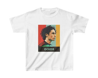 May include: White t-shirt with a retro-style graphic of a soccer player with the name "OCHOA" printed below.