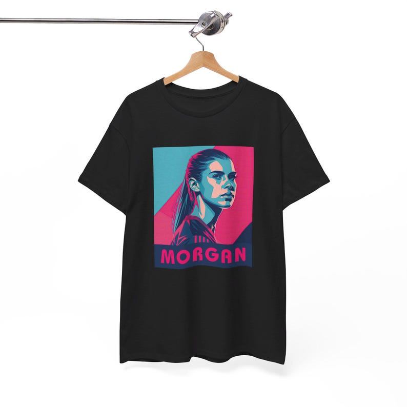 May include: Black t-shirt with a graphic of a woman's face in a blue and pink color scheme. The text "MORGAN" is printed below the image.