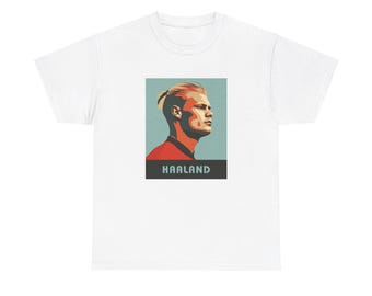 May include: White t-shirt with a graphic of a blonde man with a red and orange shirt and the word "HAALAND" in black text.
