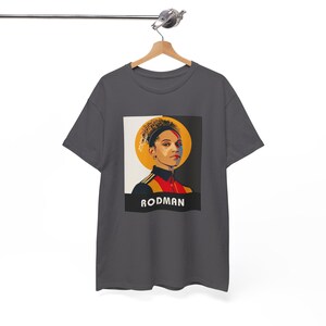May include: A dark gray t-shirt with a graphic print of a person with a yellow halo and the word "RODMA