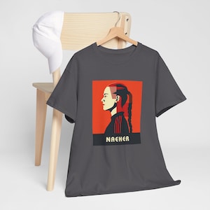 May include: Dark grey t-shirt with a red and white graphic of a woman's face with the word "NACHER" printed below.
