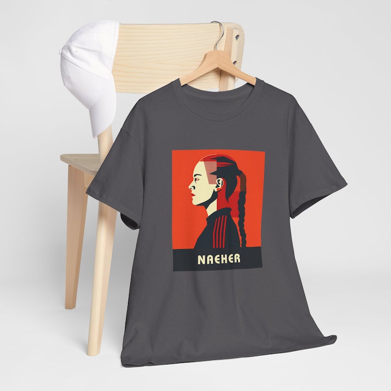 May include: Dark grey t-shirt with a red and white graphic of a woman's face with the word "NACHER" printed below.
