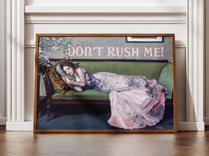 May include: A framed painting of a woman in a pink and white gown lying on a green velvet couch. The woman is asleep and the painting has the text "DON'T RUSH ME!" in pink letters.