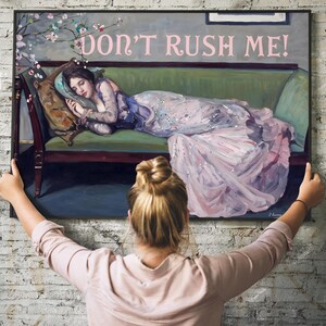 May include: A framed painting of a woman in a pink dress lying on a green couch. The painting has the text "DON'T RUSH ME!" in pink letters at the top.