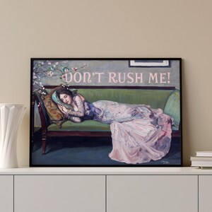 May include: A painting of a woman lying on a green velvet couch. She is wearing a pink and white dress and has her head resting on a pillow. The text "DON'T RUSH ME!" is written in pink letters above her head.