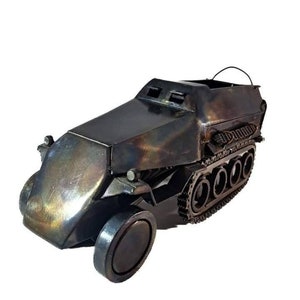 May include: A detailed model of a military half-track vehicle made of metal. The model is painted in a dark gray color with a metallic sheen. The vehicle has a track on one side and a wheel on the other.
