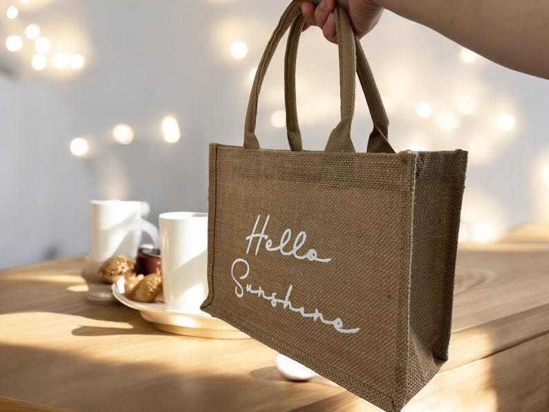 May include: A brown burlap tote bag with white lettering that says "Hello Sunshine".