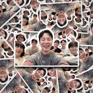 May include: A sticker sheet featuring multiple images of a group of smiling people. The central image shows a group of young men posing for a selfie. The stickers are white with a glossy finish.
