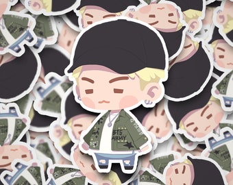 May include: A cartoon sticker of a young person wearing a green jacket with the text "BTS ARMY" on it, a black baseball cap, and blue jeans. The sticker has a white outline.