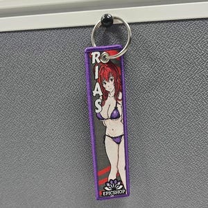 May include: Purple keychain with a cartoon anime woman wearing a bikini and the text "RIAS" and "EPICSHOP".