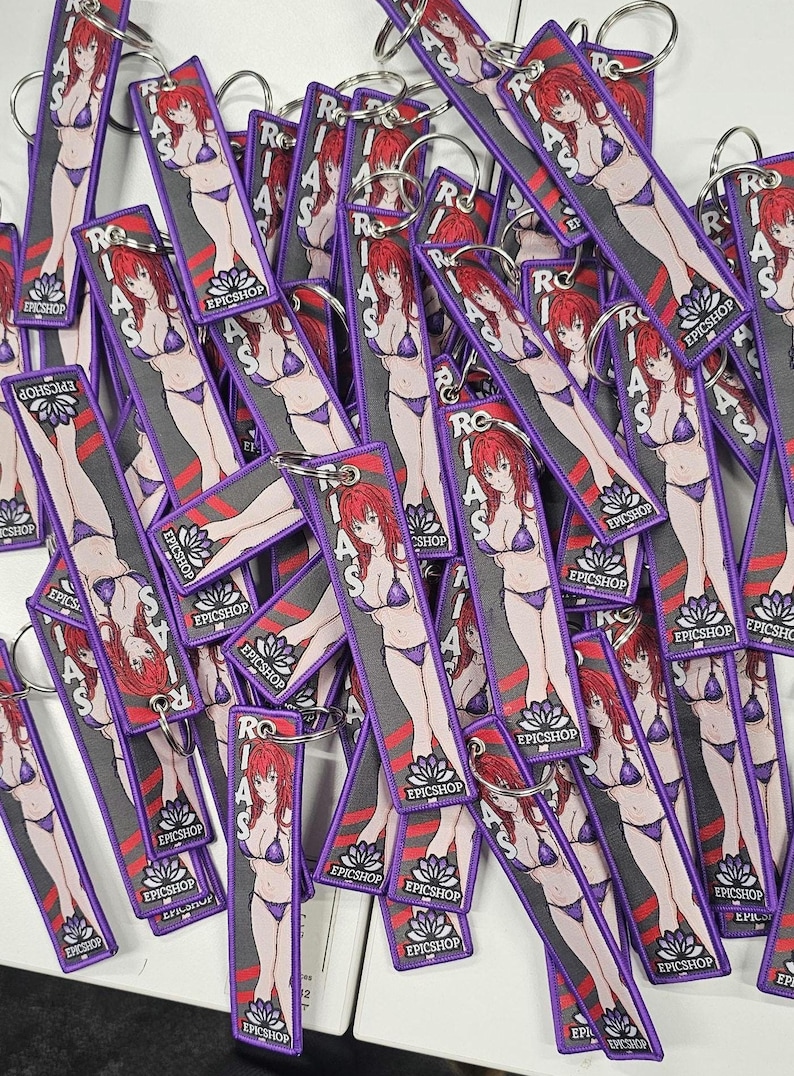May include: A pile of purple keychains with a cartoon image of a woman in a bikini. The keychains have the text "RIAS" and "EPICSHOP" printed on them.