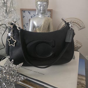 May include: A set of three ceramic mugs with a speckled, matte finish. The mugs are in shades of cream, light gray, and dark gray. Each mug has a simple, minimalist design and a rounded handle.