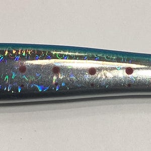 May include: A silver and blue utility knife shaped like a fish with red spots. The blade is visible and extends from the fish's tail.