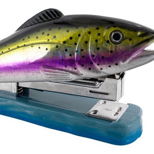 May include: A colorful fish-shaped stapler with a silver base and a blue plastic base. The fish is painted with a green, yellow, purple, and black pattern.