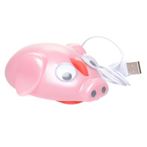May include: A pink pig-shaped computer mouse with googly eyes and a red nose. The mouse is connected to a white USB cable.