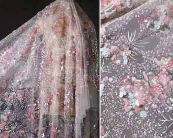 以下が含まれることがあります： ピンク、白、水色の色合いで、複雑な刺繍と虹色のスパンコールが施されたシースルー生地。この素材は、繊細な糸細工と、全体に散りばめられたきらめく円形のスパンコールによる花柄のデザインが特徴です。