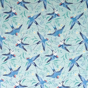 May include: A repeating pattern of blue swallows with red accents and white bellies, set against a light teal background with white and green floral elements. The swallows are depicted in various flying positions.
