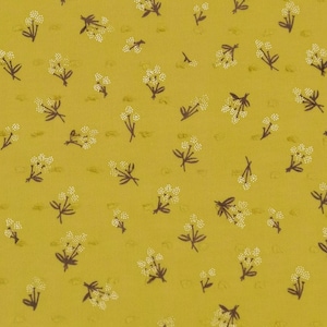 Op de afbeelding: Een gele stof met een wit en bruin bloemenpatroon. De stof heeft een textuur.